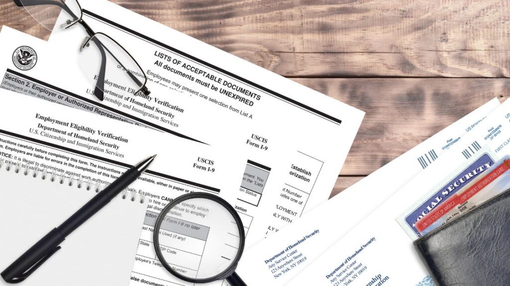 Stack of completed Form I-9 employment eligibility verification documents on an office desk